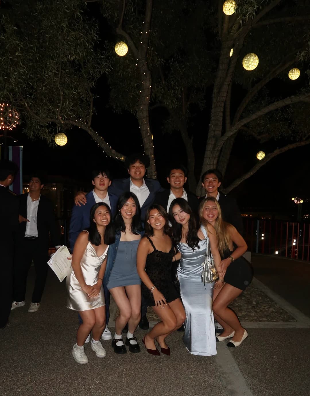 Group dressed up at an evening event under a lit tree