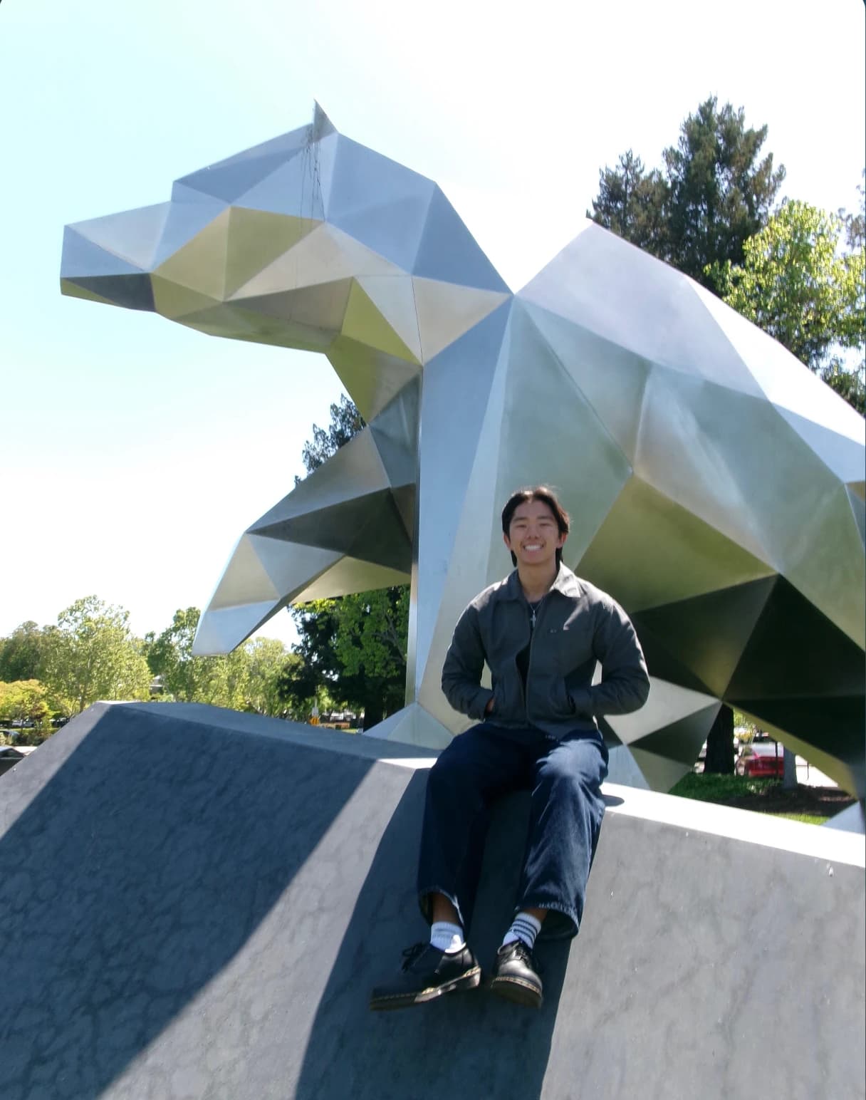 Ryan sitting in front of a large metal wolf sculpture